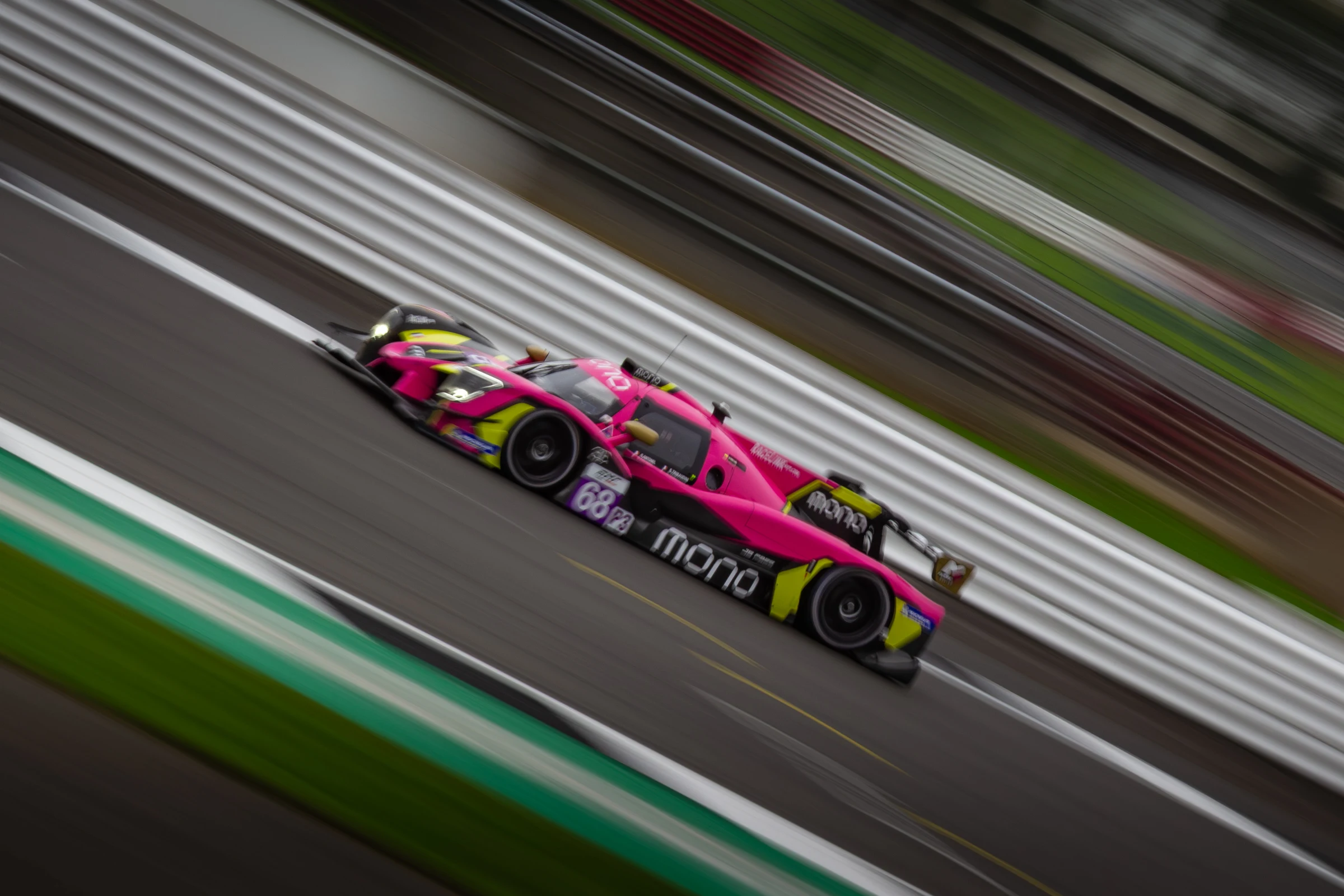 Pink and yellow number 68 prototype in a diagonal panning shot at Silverstone